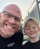 Justin Jordan and his son at a racetrack at dusk, both in Southern Performance shirts